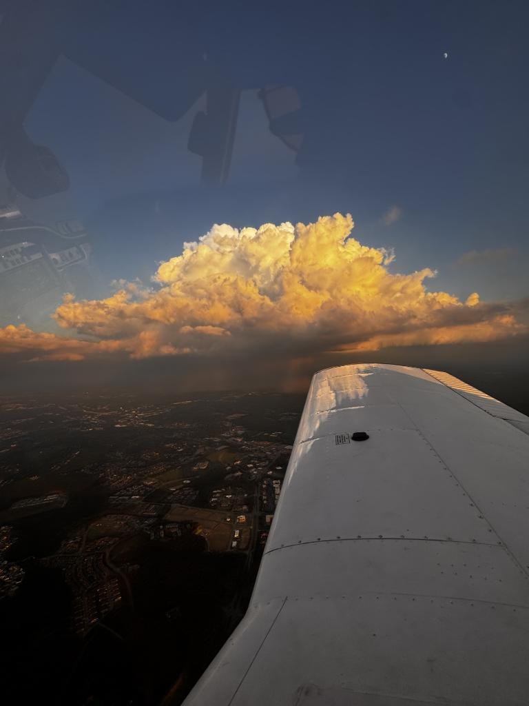 Aircraft wing at sunset with golden storm clouds